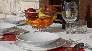 A table set with plates, a bowl of fruit, wine glasses, and a bottle of wine.