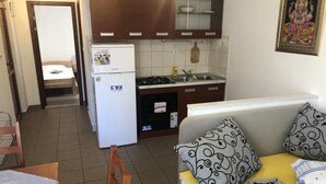 Une cuisine compacte équipée d’un réfrigérateur, d’une cuisinière et d’un évier. On y trouve également un petit coin repas avec une chaise et une table.
