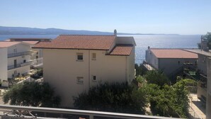 Un quartier résidentiel en bord de mer, caractérisé par des bâtiments aux toits de tuiles en terre cuite, des balcons et une vue dégagée sur la mer.