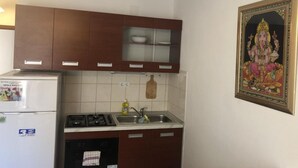 Une cuisine avec des meubles de rangement en bois, une cuisinière à gaz, un évier et un réfrigérateur.
