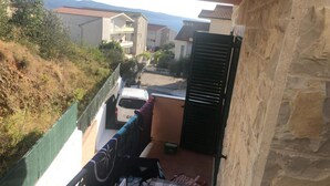 Un balcón con una mesa, sillas y vistas a un coche blanco y edificios al fondo.