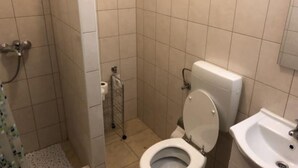 Un baño pequeño con azulejos, que incluye un inodoro, un lavamanos y una zona de ducha.