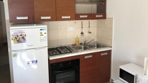 Una cocina compacta equipada con refrigerador, estufa, horno, pileta y microondas.