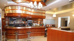 Un'area bar moderna con un bancone in legno curvo, sgabelli da bar e un lampadario.