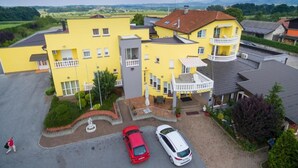 Un edificio giallo con un balcone, un'area di parcheggio e vista sulla campagna.