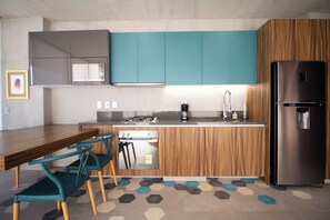 Enjoy cooking in this kitchen with a sleek refrigerator, microwave, and compact stove, complemented by a wooden countertop and teal cabinetry.