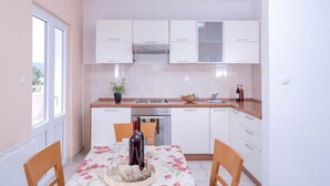 Une cuisine compacte avec des meubles blancs, un plan de travail en bois et une table à manger pour deux personnes.