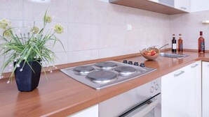 Une cuisine moderne avec un plan de travail en bois, une cuisinière à gaz, des placards blancs et une plante en pot.