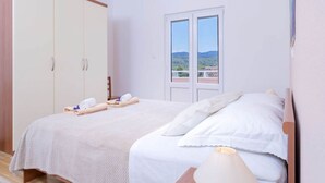 Une chambre à coucher comprenant un lit, une armoire, une fenêtre avec vue et un luminaire au plafond.