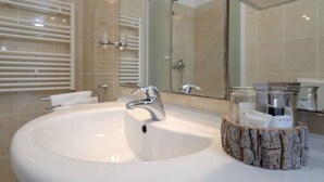 A modern bathroom with a large white sink, a mirror, and a towel rack.