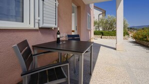 An outdoor patio with a table and chairs, a bottle of wine, and a view of the surrounding landscape.