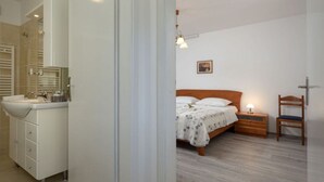 A bedroom with a wooden bed, bedside table, and chair.