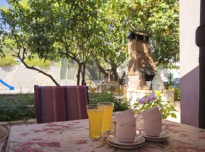 A table with a floral tablecloth, two glasses of yellow beverage, and three stacked cups.