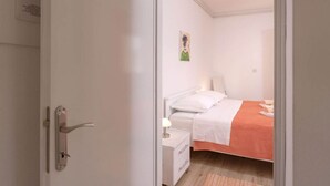 A bedroom with a bed, bedside table, and a painting on the wall. - One Bedroom Apartment with Terrace (Vrboska)