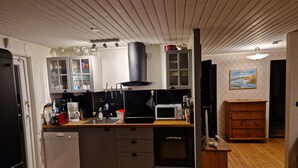 Eine Küche mit Kochinsel, Mikrowelle, Herd und Spüle. Es gibt einen Holzschrank und einen kleinen Holztisch.
