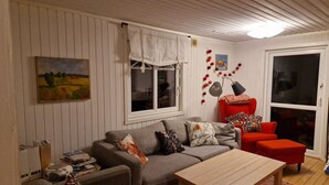 Ein gemütliches Wohnzimmer mit einem grauen Sofa, einem roten Sessel und einem Couchtisch aus Holz.