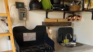A kitchen with a gas stove, sink, and a trash bin. - The Greenhouse - New River Gorge National Park (Rainelle)