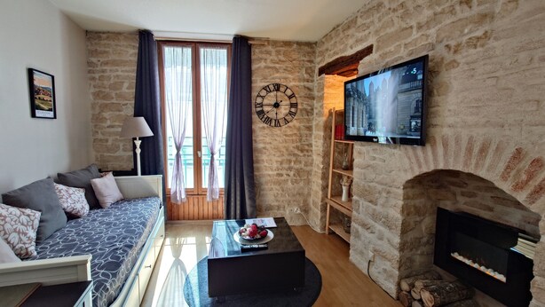 A living room with a stone wall, a sofa, a coffee table, a fireplace, and a TV mounted on the wall.