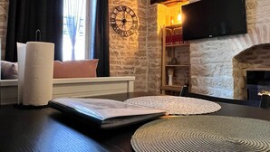 A cozy living room with a stone wall, a fireplace, a flat-screen TV, and a large clock.