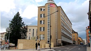A multi-story building with a curved corner, featuring a prominent 'SNCF' sign on the top.