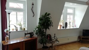 A room with a sewing machine on a wooden table, a large potted plant, and a small table with a teapot and cups. - Duplex apartment over 2 levels with roof terrace near the Elbe in Dresden-Blasewitz (Dresden)