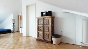 A room with a wooden floor, a patterned cabinet, a radiator, and a door. - Duplex apartment over 2 levels with roof terrace near the Elbe in Dresden-Blasewitz (Dresden)