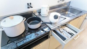 A compact kitchen with a stove, a pot, a kettle, and a toaster. - Suzuka Smile Room (Suzuka)