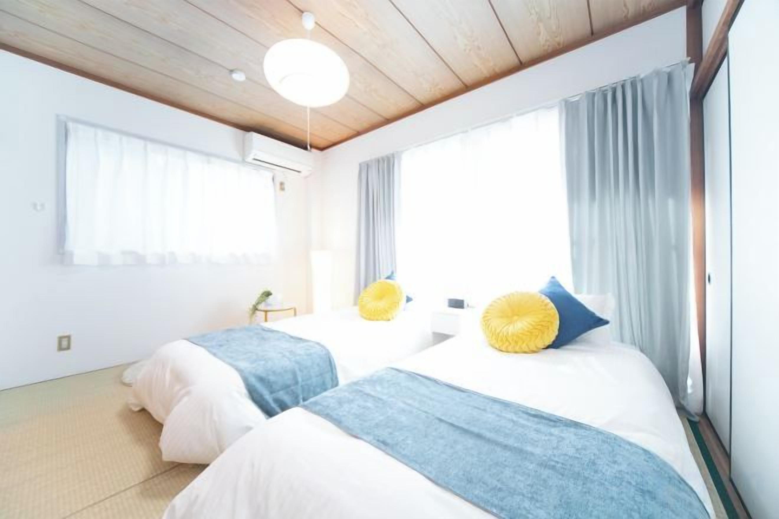 Habitación de hotel con dos camas, techo de madera y un ventanal grande con cortinas.