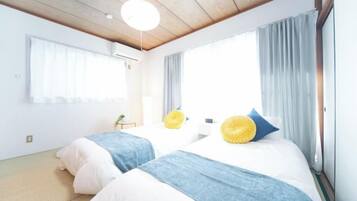 Habitación de hotel con dos camas, techo de madera y un ventanal grande con cortinas.