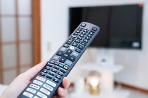 A hand holding a remote control with multiple buttons. - Suzuka Smile Room (Suzuka)