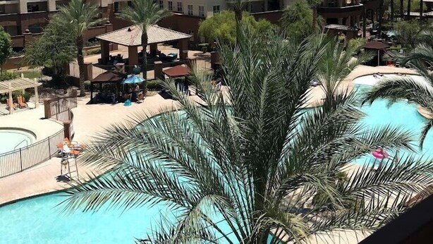 A hotel with a swimming pool, palm trees, and a view of mountains. - WorldMark Spencer Street - 1 Bedroom (Las Vegas)