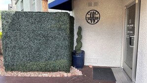 A building entrance with a hedge, a potted tree, and a sign indicating 'WORLDMARK' and 'Lobby Hours.' - WorldMark Spencer Street - 1 Bedroom (Las Vegas)