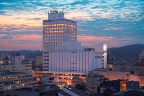 A modern high-rise building with a prominent glass facade, surrounded by other buildings in a cityscape.