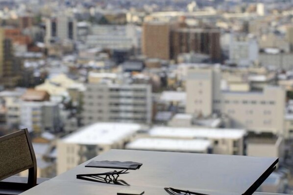 A table with a cityscape view, a chair, and a pair of glasses.