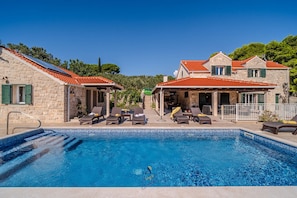 A poolside area with lounge chairs and a swimming pool. - Luxury 4BR Seafront Villa with Heated Pool (Milna)