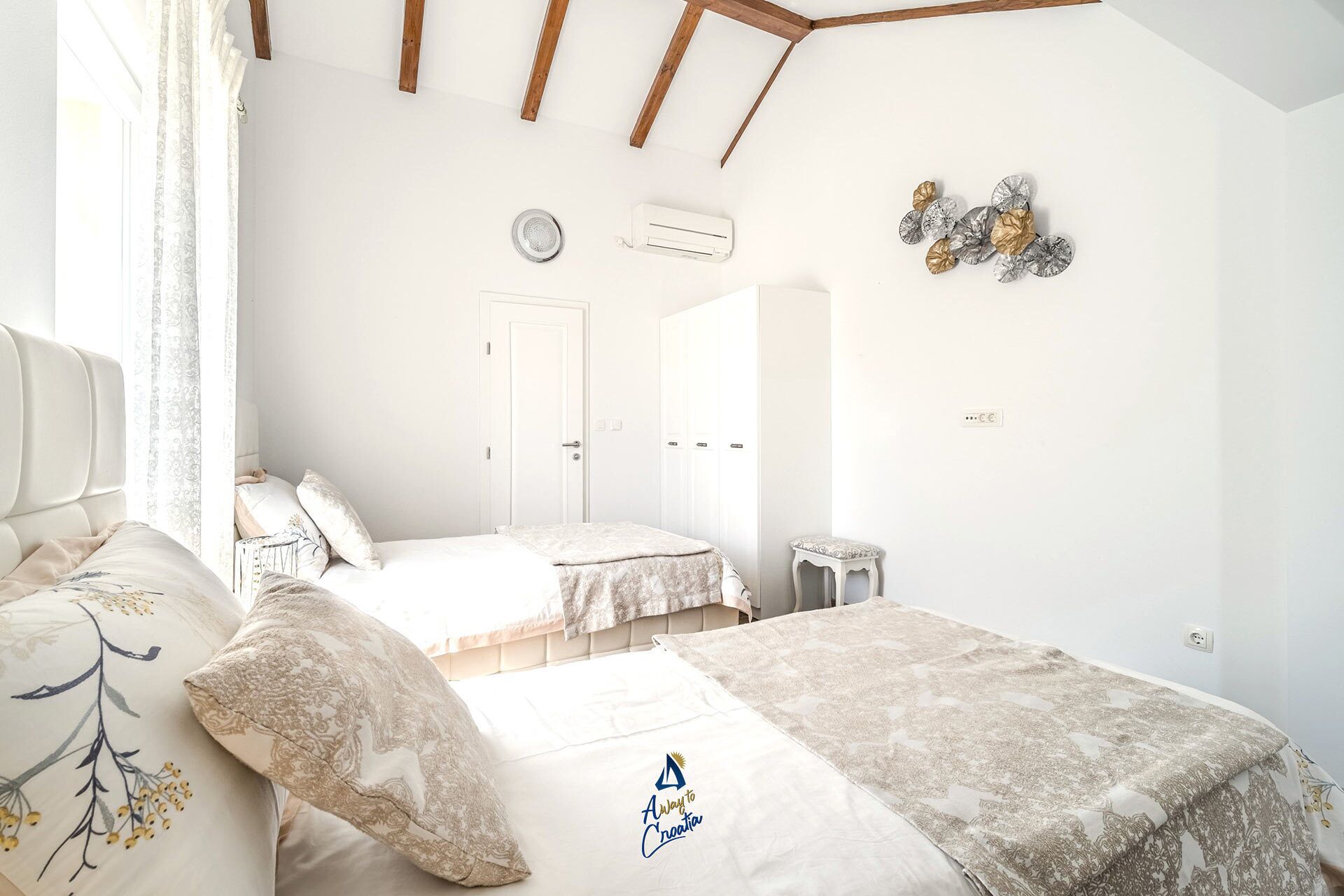 A bedroom with two beds, a small table, and a door.