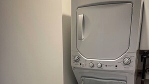 A front-loading washing machine with a control panel, a door, and a shelf with laundry detergent. - **Cleaning Fee Included** Mini modern cabin nestled in the peaceful hills between Jackson and Putnam County, minutes away from CUMMINS FALLS STATE PARK. Designed for comfort and style, this vacation rental seamlessly blends modern charm with wooded s (Cookeville)