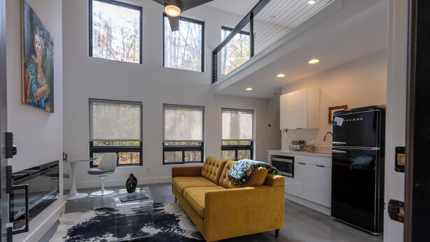 A modern kitchen with a black refrigerator, white cabinets, and a dining area with a white chair and a glass table. - **Cleaning Fee Included** Mini modern cabin nestled in the peaceful hills between Jackson and Putnam County, minutes away from CUMMINS FALLS STATE PARK. Designed for comfort and style, this vacation rental seamlessly blends modern charm with wooded s (Cookeville)