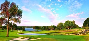 Un campo de golf con búnkeres de arena, un estanque y árboles.