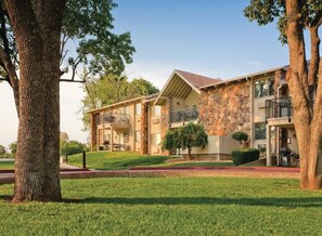 A two-story building with stone facade, balconies, and a well-maintained lawn.