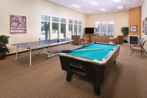 A pool table, ping pong table, and a television in a room with large windows and a carpeted floor. - Grand Lake | Couples Lake Retreat | Pool + Hot Tub (Afton)