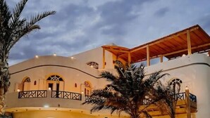 A multi-story building with a stone facade, arched windows, and a covered outdoor area.