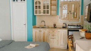 A compact room with a bed, a small kitchenette, and a dining area.
