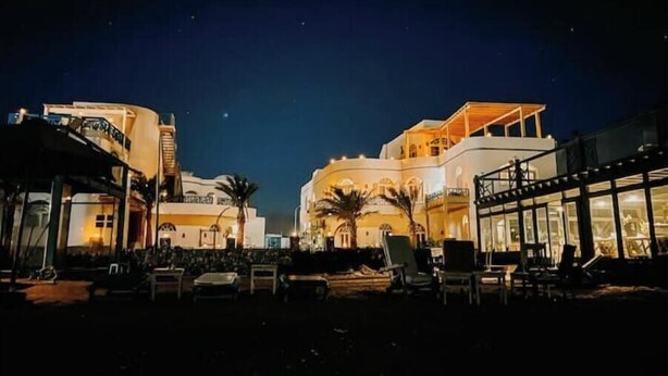A hotel with a large, illuminated building and outdoor seating area.