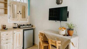 A compact kitchen with wooden cabinets, a built-in stove, a small refrigerator, and a dining area with a table and chairs.