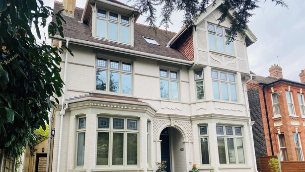 A two-story house with a bay window, a brick facade, and a small front garden.
