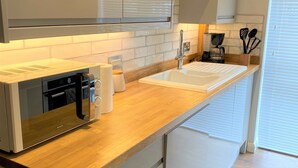 A modern kitchen with a wooden countertop, white cabinets, and a built-in dishwasher.