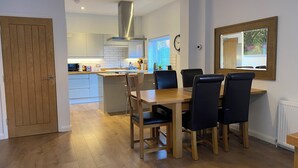 A modern kitchen with white cabinets, a wooden dining table, and black chairs.