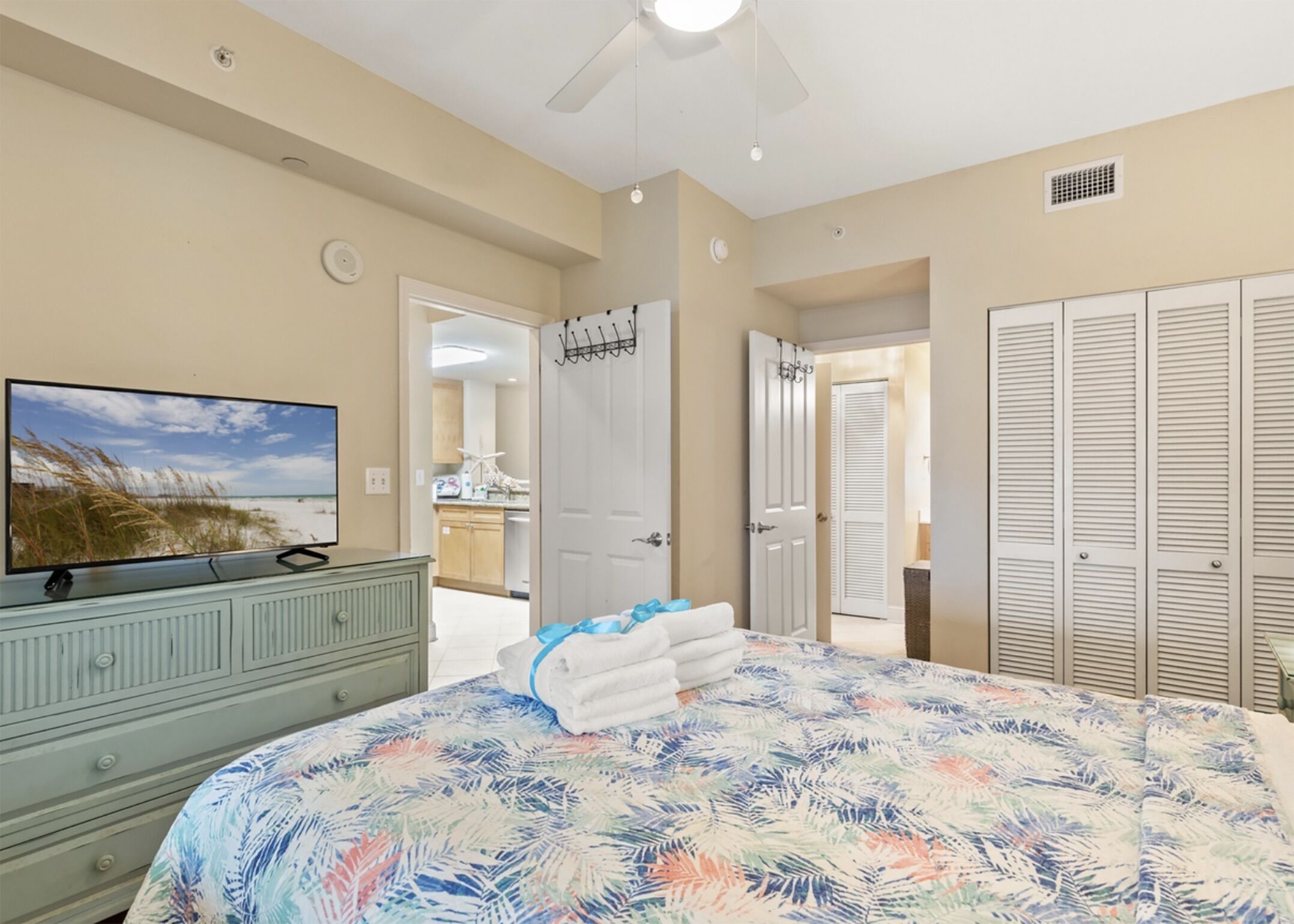 A bedroom with a bed, a dresser, a television, and a closet.