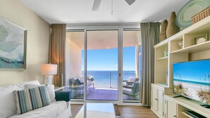 Ein modernes Wohnzimmer mit einer Couch, einem Couchtisch, einem Flachbildfernseher und einem Balkon mit Meerblick.